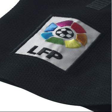 Primer plano del parche tridimensional de la LFP en la manga derecha del jersey Nike del FC Barcelona. Textura de tejido Dri-FIT visible, calidad de archivo histórico.