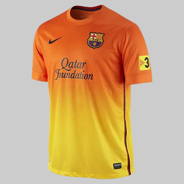Vista angulada del jersey Nike Lio Messi FC Barcelona de visitante 2012/13 (Ref. 478326-815) en stock en  Futbol90MX, mostrando el característico diseño con degradado de naranja a amarillo, el patrocinio de Qatar Foundation y el escudo del club
