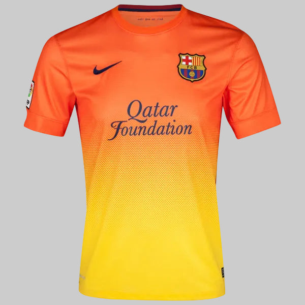 Primer plano del pecho del jersey Nike FC Barcelona 2012/13 de Messi (Ref. 478326-815) en Futbol90MX, mostrando el escudo bordado del club, el logotipo de Nike y el patrocinio de Qatar Foundation sobre el fondo degradado