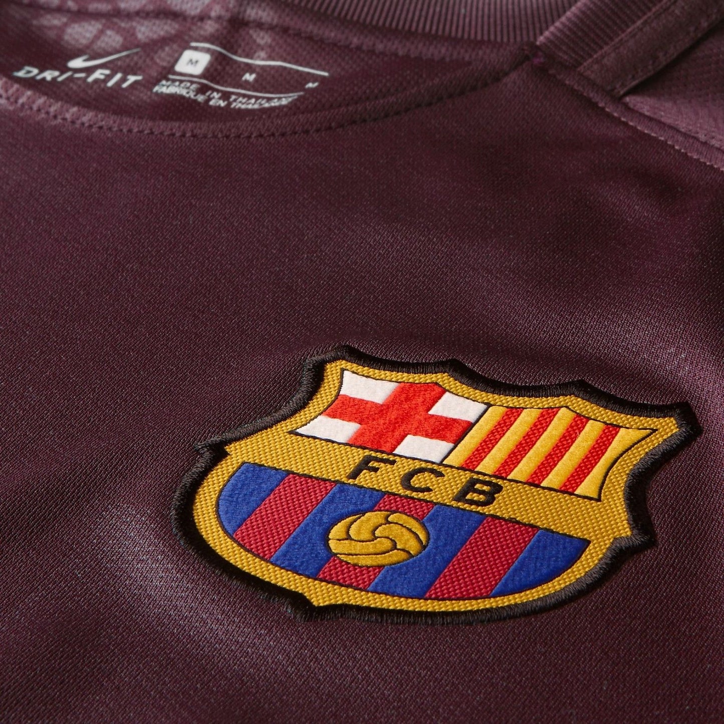 Detalle bordado del escudo oficial del FC Barcelona sobre el fondo color burdeos del jersey de Messi de competiciones europeas de la temporada 2017/18 (Código: 847253-683) en Futbol90MX.