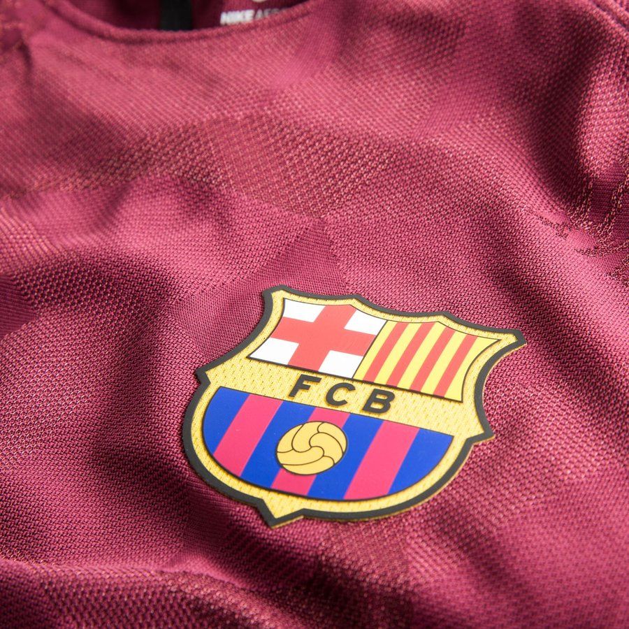Detalle en primer plano del escudo oficial del FC Barcelona termosellado de alta precisión sobre la textura de tejido técnico AeroSwift color granate del jersey t ercero Vapor Match de Messi UCL 2017/18 (Código: 847188-683) en Futbol90MX.