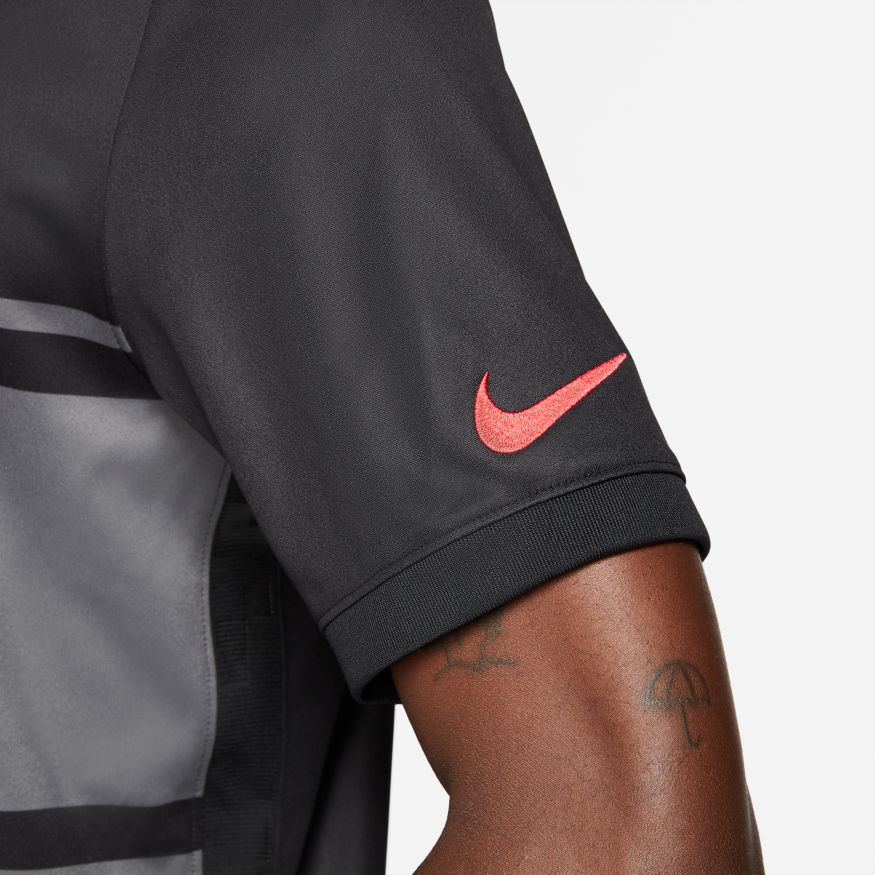Vista de detalle de la textura del tejido Nike Dri-FIT y el logo Swoosh en rojo, destacando la calidad de los materiales de este uniforme histórico.