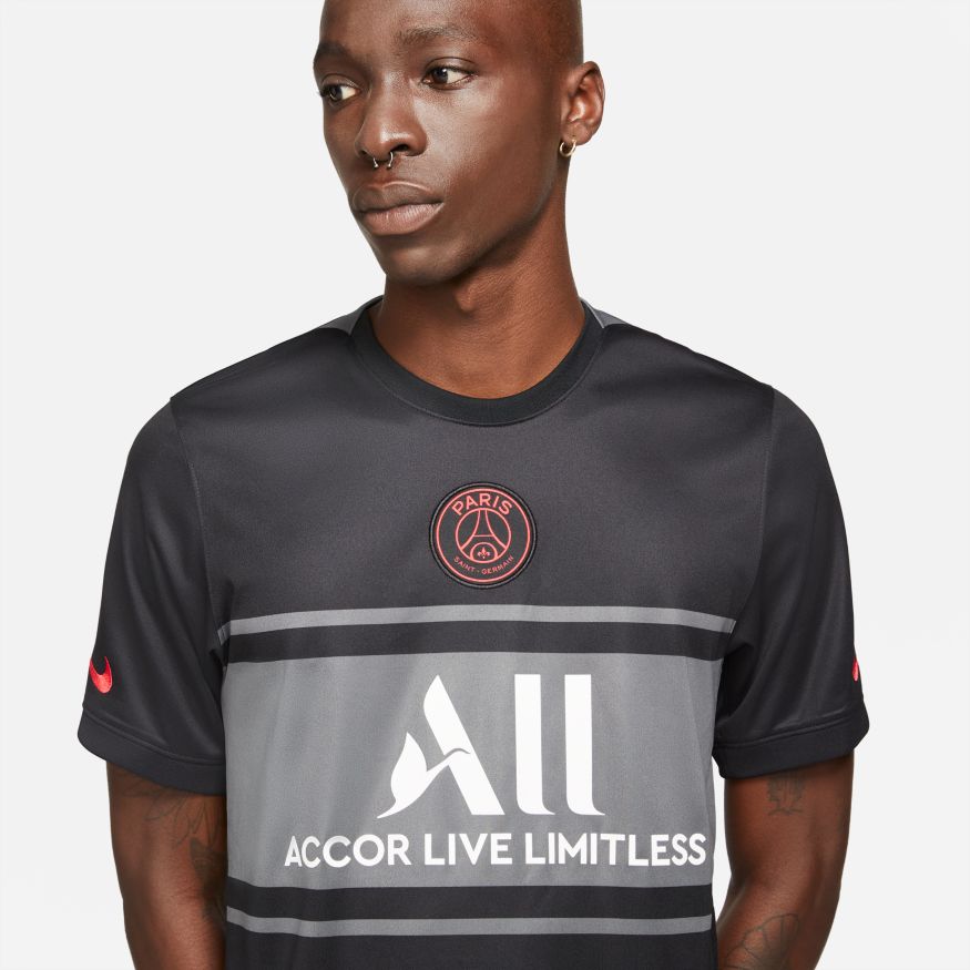 Vista cercana del escudo circular del PSG aplicado en el centro del pecho, contrastando sobre el tejido negro premium del jersey Nike Third de Lionel Messi 2021-22