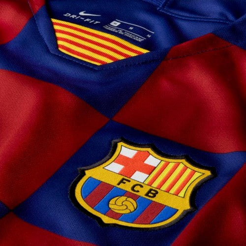 Primer plano detallado del jersey local Nike del FC Barcelona de Suarez 2019/20 (Ref. AJ5532-456), mostrando el escudo bordado del club, el revolucionario patrón de cuadros azulgrana y la etiqueta interior con el cuello en V adornado con la bandera de la Senyera en Futbol90MX
