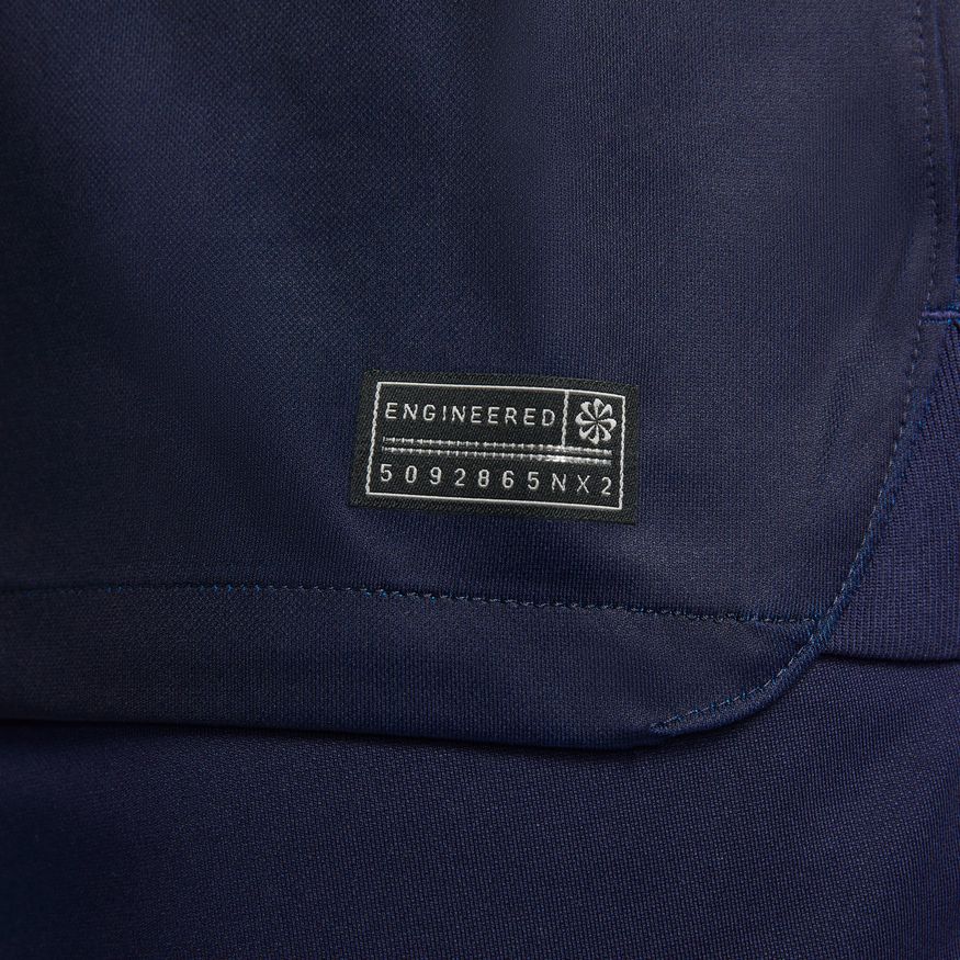 Acercamiento a la etiqueta de autenticidad en el dobladillo inferior, validando la tecnología Nike Dri-FIT y el código de fábrica DN0661-498.