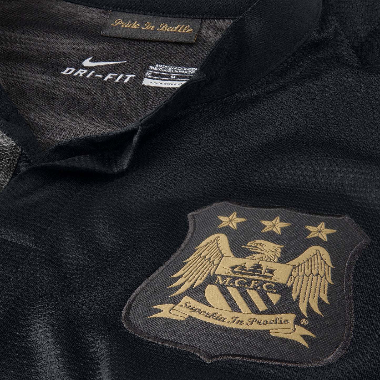 Escudo del Manchester City bordado en hilo dorado sobre el panel negro del jersey de visita 2013/14.
