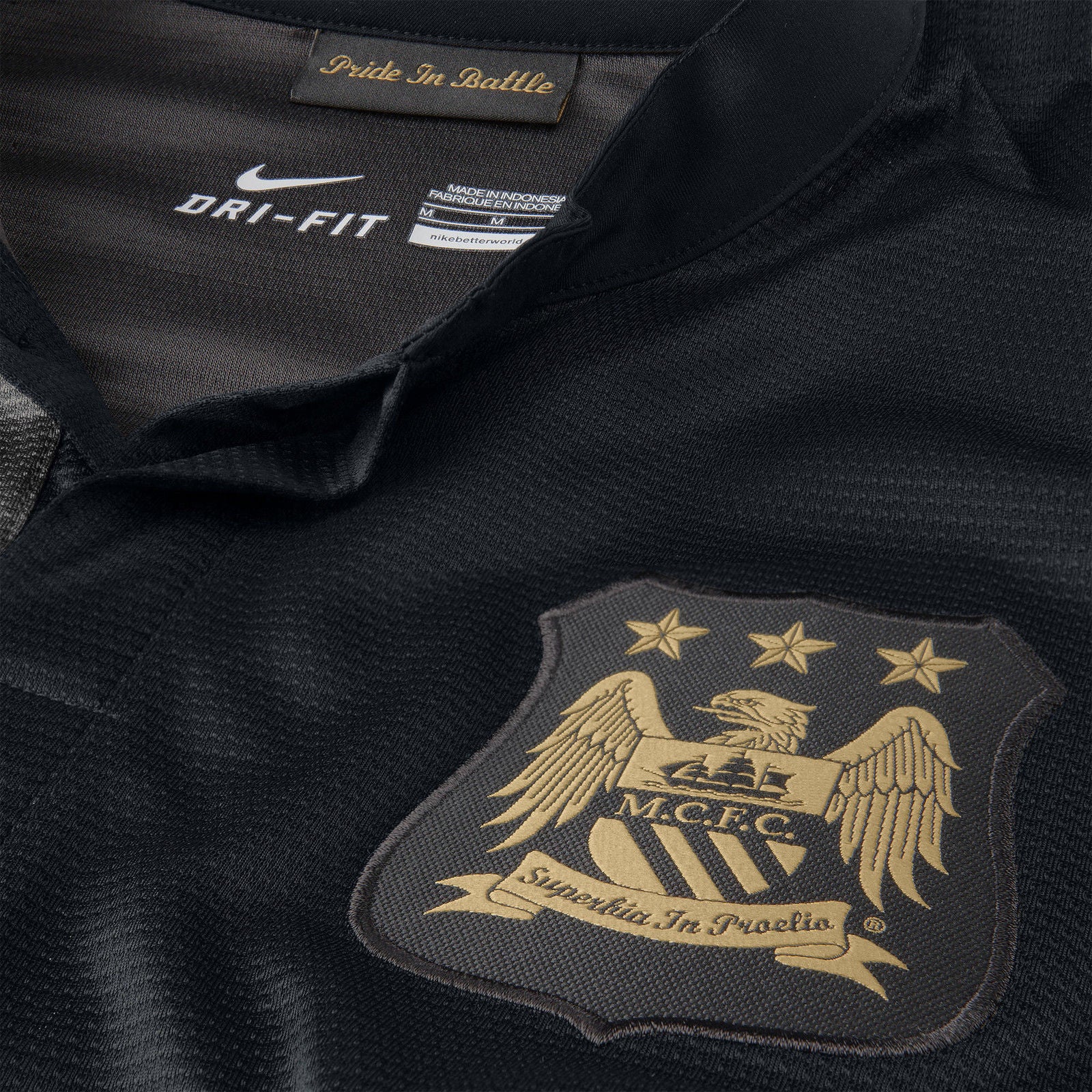 Escudo del Manchester City bordado en hilo dorado sobre el panel negro del jersey de visita 2013/14.