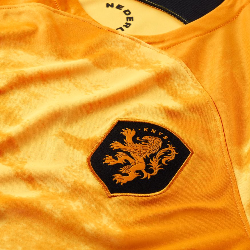 Detalle del escudo de la KNVB en color negro, bordado de alta densidad sobre el tejido satinado naranja oficial de Nike.