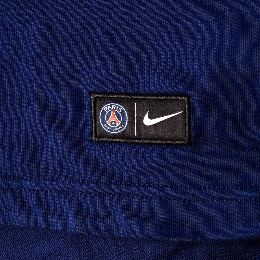 Primer plano del dobladillo inferior de la sudadera, mostrando la etiqueta tejida oficial de Nike y el escudo del Paris Saint-Germain, en Futbol90MX