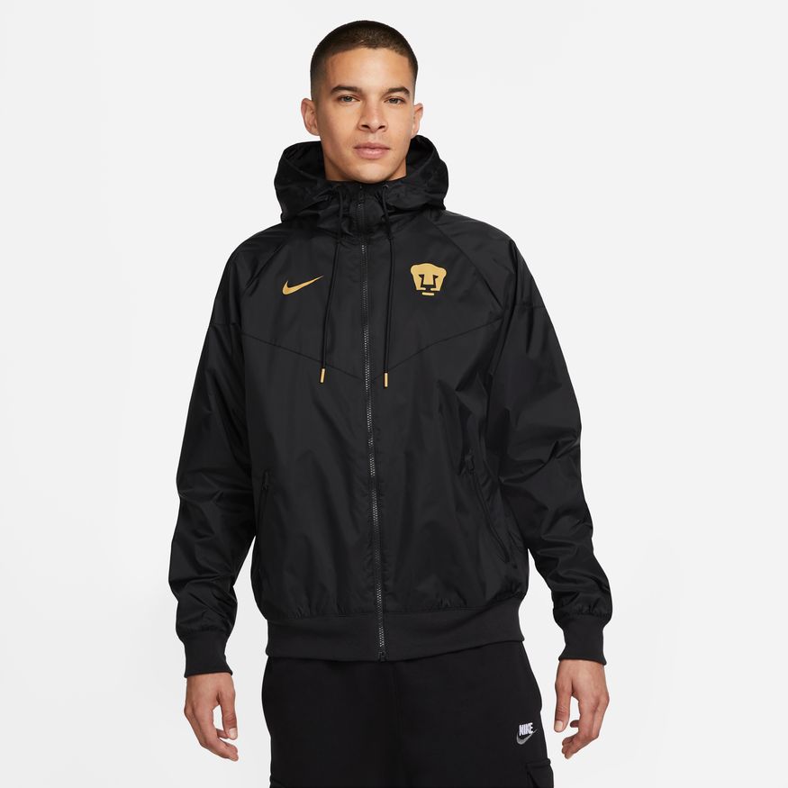 Vista frontal completa de la chamarra rompevientos Nike Pumas UNAM Windrunner 2023 en color negro con detalles dorados satinados en Futbol90MX