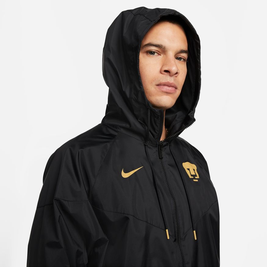 Acercamiento superior a la capucha de paneles ajustables y al cierre de cremallera frontal de la chamarra Nike Pumas Windrunner 2023 en Futbol90MX