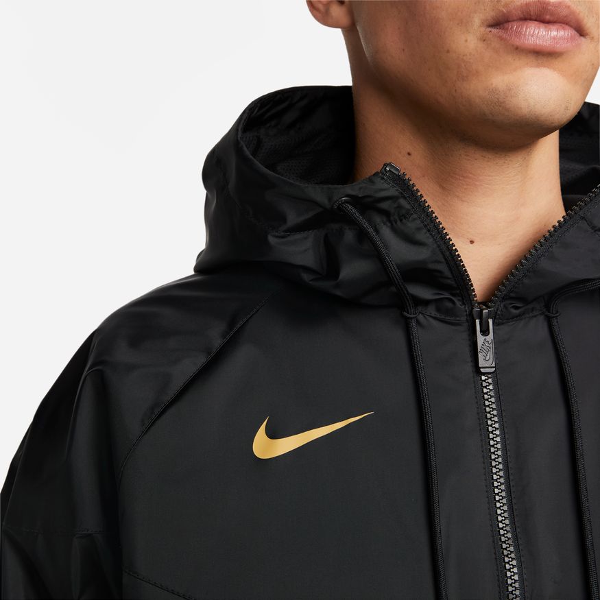 Acercamiento al pecho de la rompevientos Nike de Pumas 2023, mostrando el Swoosh de Nike termoaplicado en oro.