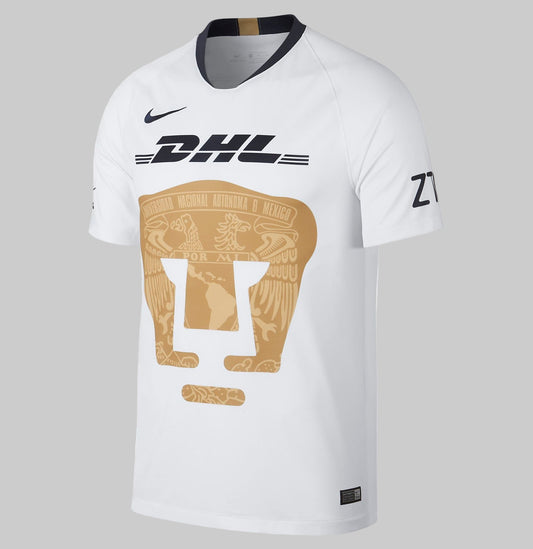 Jersey de local Nike 919013-101 Pumas UNAM 2018/19 en blanco clásico con el icónico escudo del Puma en dorado ocupando el centro del pecho.