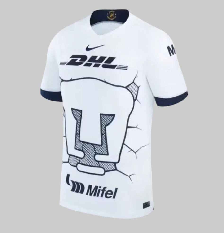 Vista lateral del jersey Pumas UNAM 2023/24 mostrando el ajuste Stadium Fit y los logotipos oficiales de patrocinadores en las mangas. Contraste de puños en azul obsidiana Nike DX2696-101