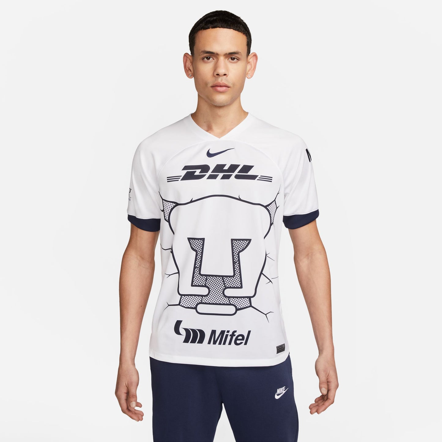 Primer plano del icónico escudo del Puma y el Nike Swoosh en el jersey de casa 2023-24. Detalle de la textura del tejido Dri-FIT y el patrón de grietas tonales de alta definición.