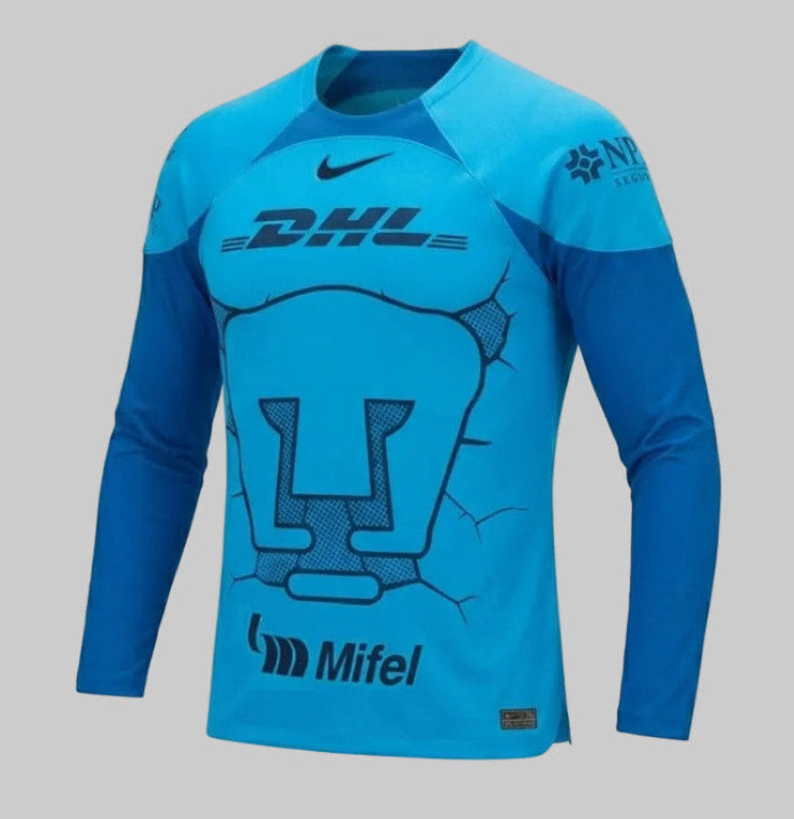 Vista técnica en ángulo de 45 grados del jersey de portero Pumas UNAM 2023-24. Formato de maniquí fantasma que muestra la estructura de manga larga y detalles del cuello Nike DX2638-407 Dri-FIT.