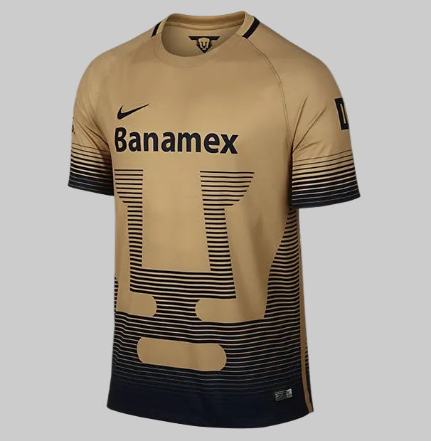 Jersey Nike 695676-724 Pumas UNAM Visitante 2015/16 en color oro metálico con el icónico escudo del Puma formado por líneas horizontales en azul marino.