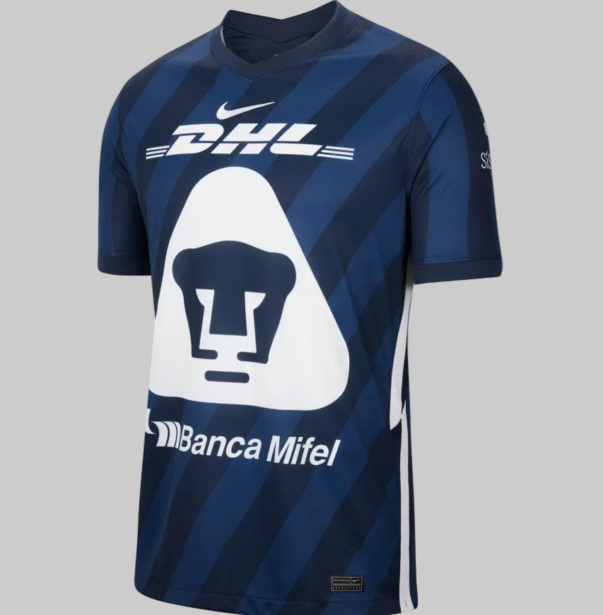 Jersey de visita Pumas 2020/21 en azul obsidiana con patrón de franjas diagonales y escudo del Puma sobre panel triangular blanco Nike CD4243-451