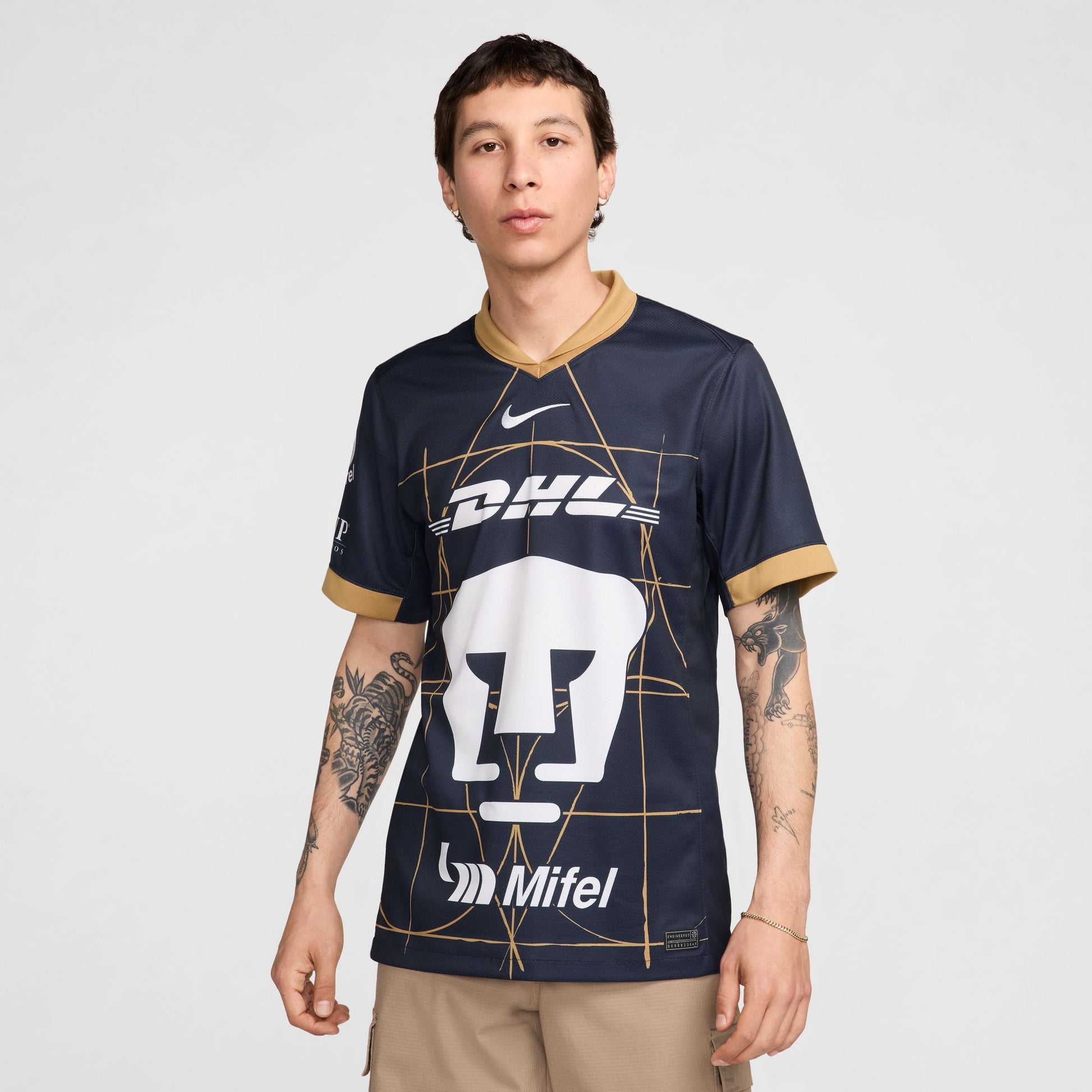 Perspectiva lateral del jersey de Pumas 2024/25 resaltando el corte atlético y el ribete dorado sólido en los puños de las mangas.