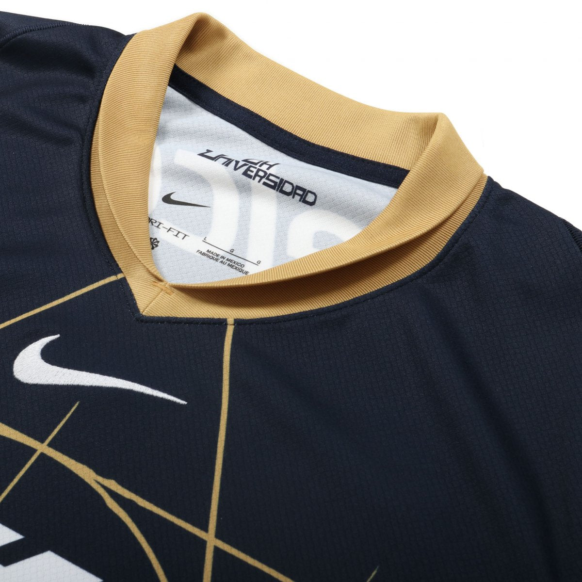 Acercamiento al cuello en "V" color oro y logotipo de Nike (Swoosh) bordado en alta densidad sobre el tejido técnico transpirable azul.