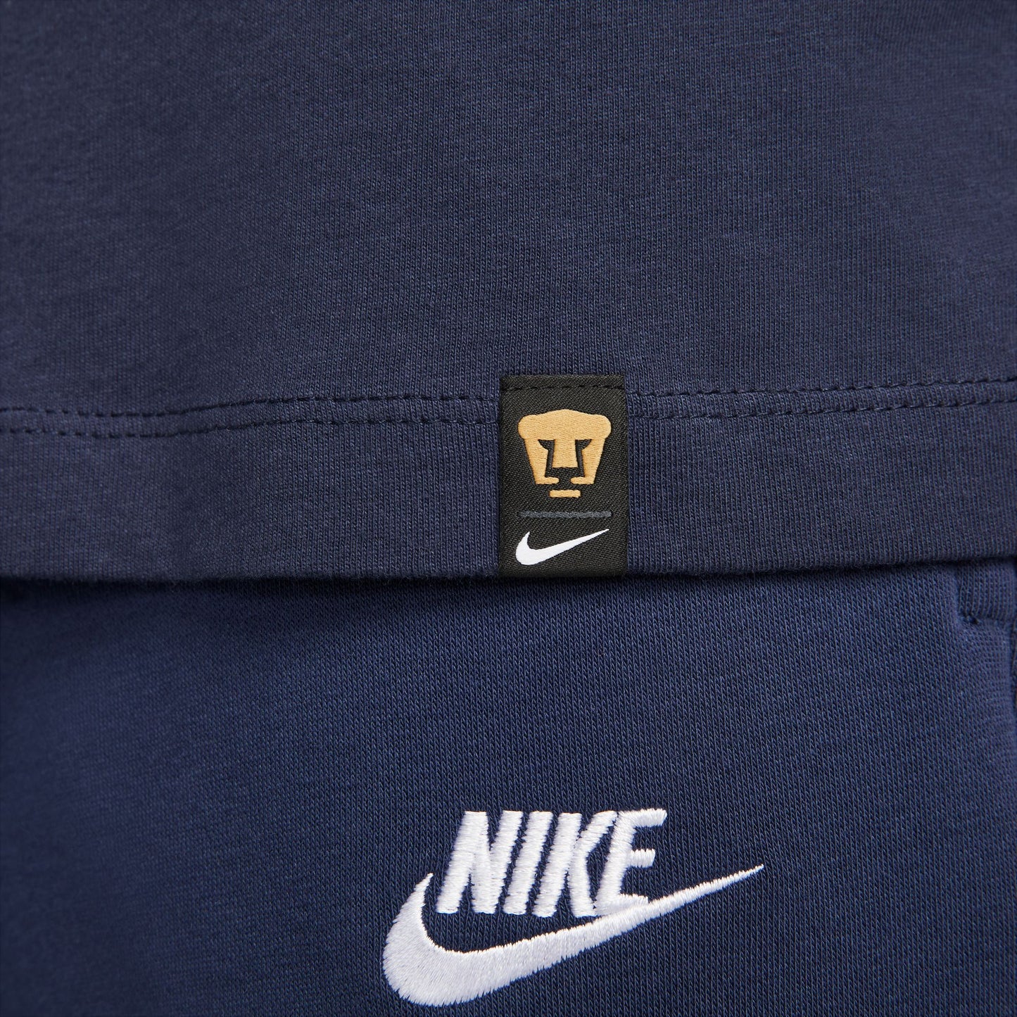 Etiqueta tejida oficial Nike x Pumas UNAM en la parte inferior, verificando el estatus de producto bajo licencia oficial.