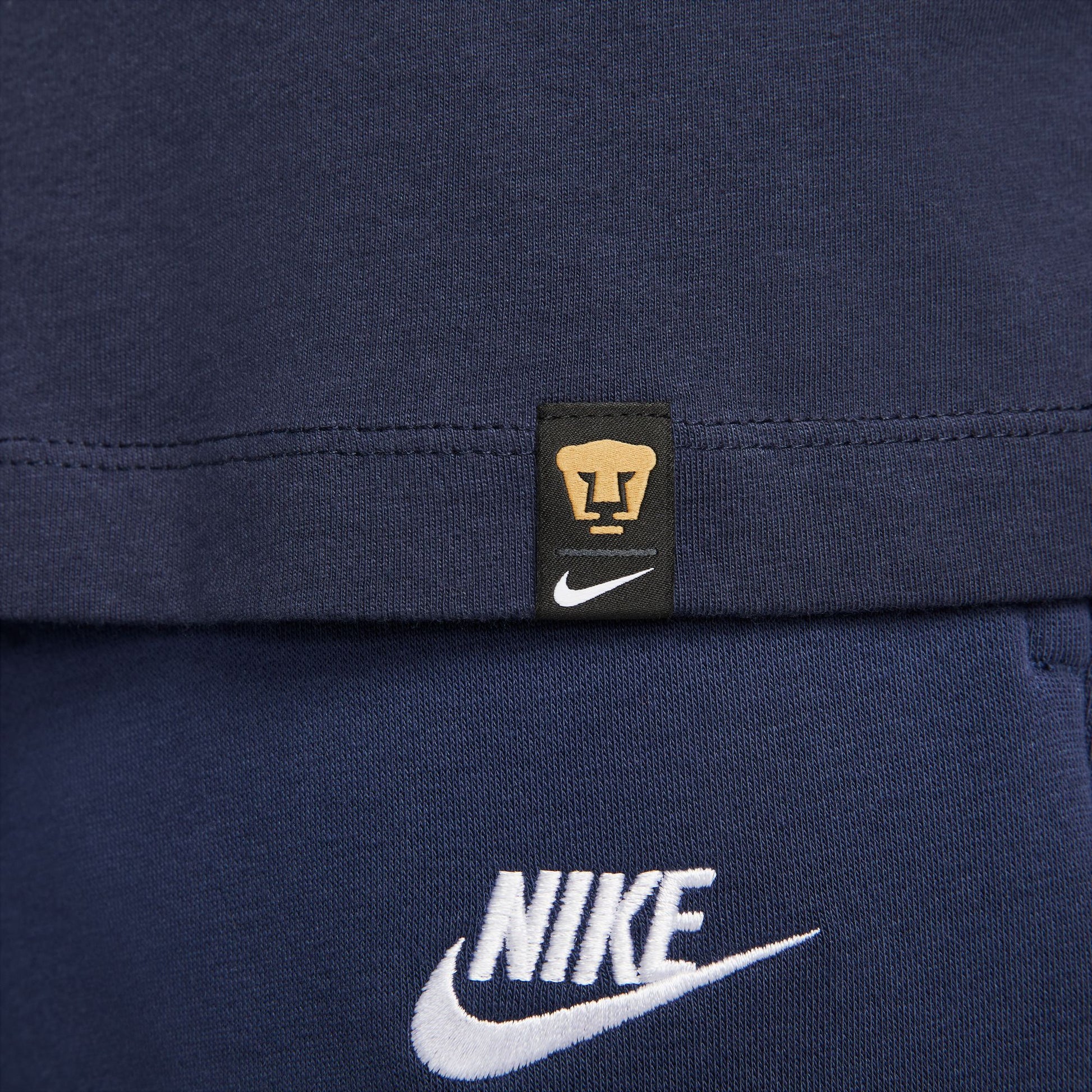 Etiqueta tejida oficial Nike x Pumas UNAM en la parte inferior, verificando el estatus de producto bajo licencia oficial.