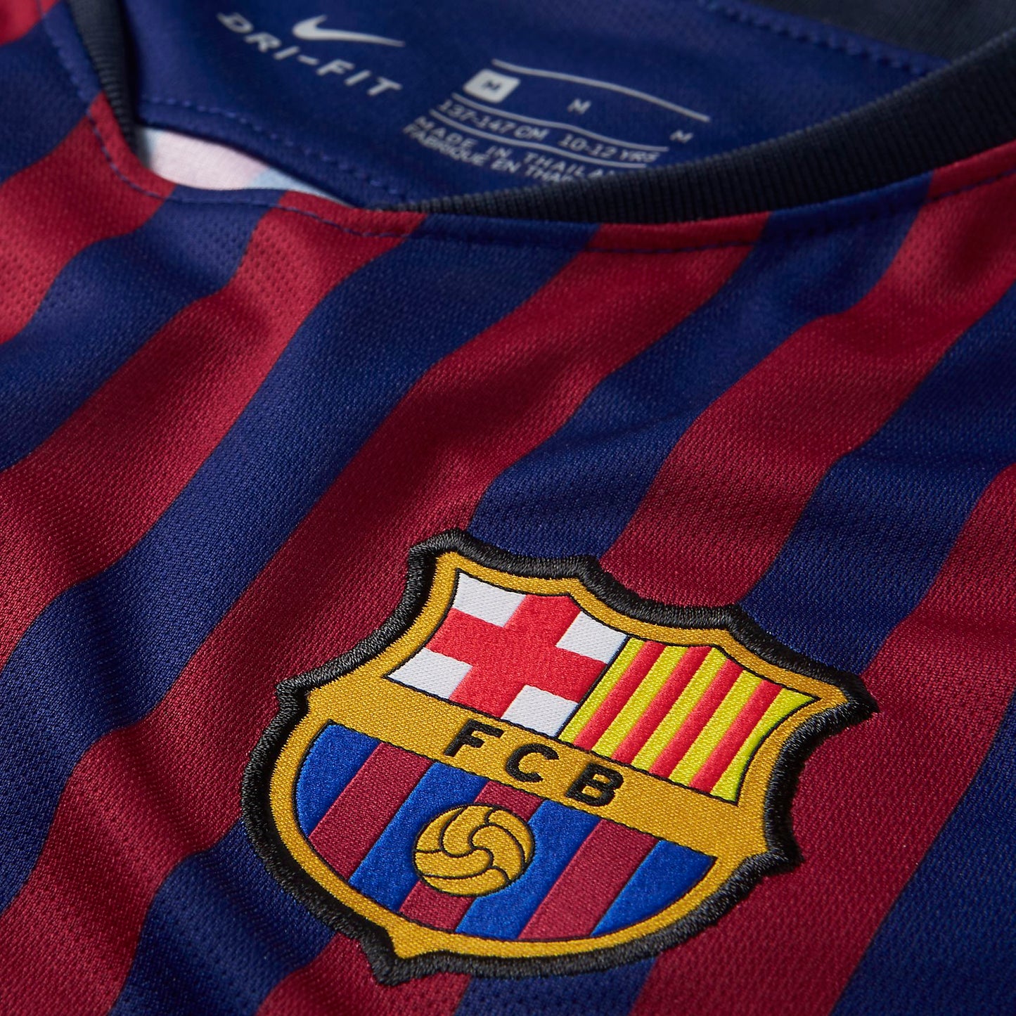 Acercamiento al escudo bordado del FC Barcelona y el Swoosh de Nike en dorado sobre el tejido de alta calidad de la equipación local 2018/19.