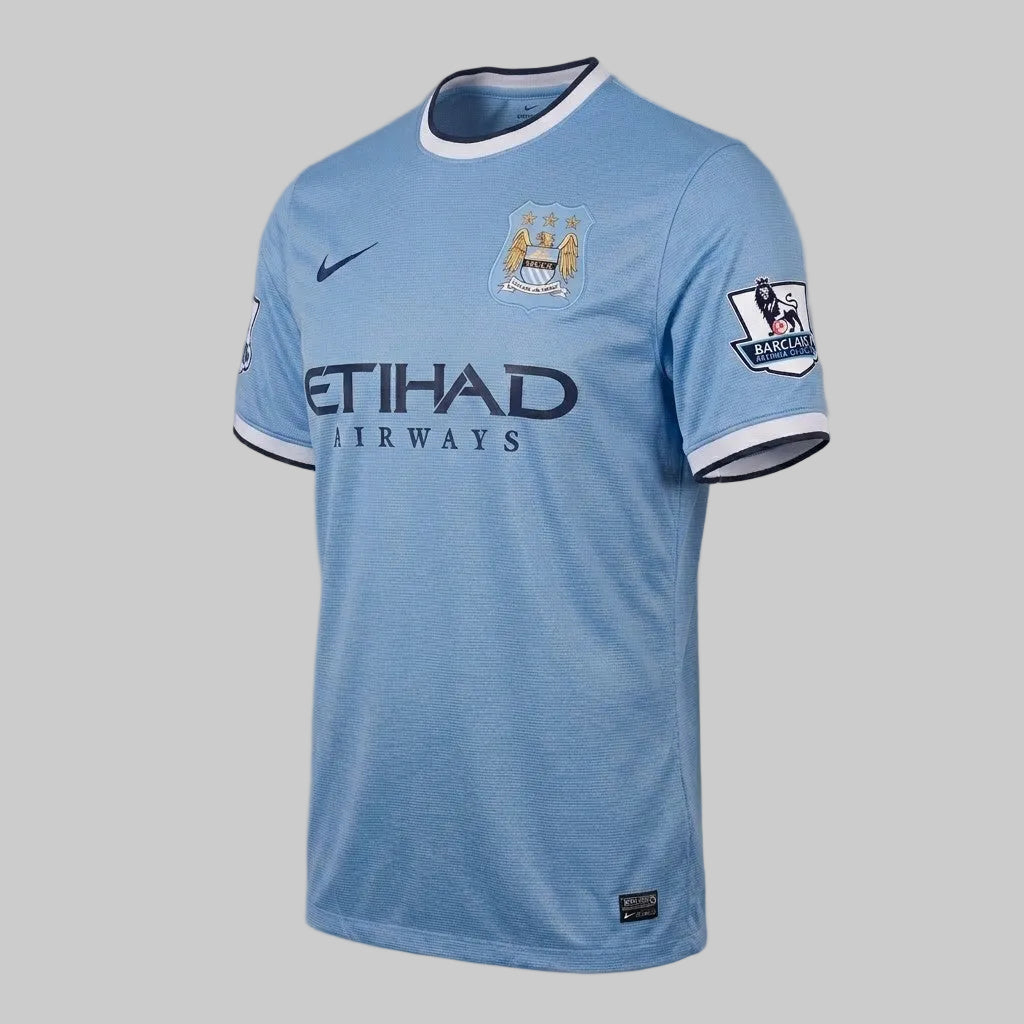 Jersey local Nike Manchester City 2013-14 color sky blue con cuello redondo y puños azul marino.