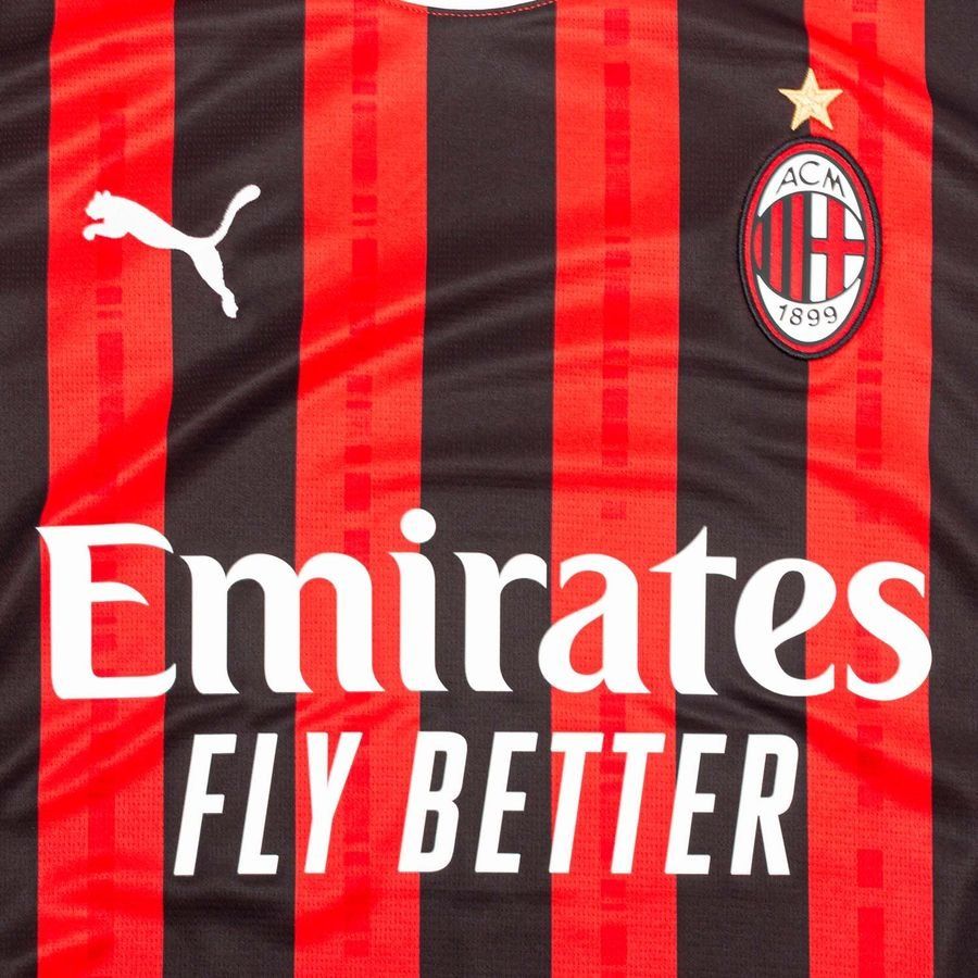 Primer plano del pecho del jersey Puma AC Milan de casa 2024/25 (Ref. 774979 01) mostrando el escudo oficial bordado con la estrella dorada, el felino de Puma y el logotipo Emirates Fly Better en Futbol90MX