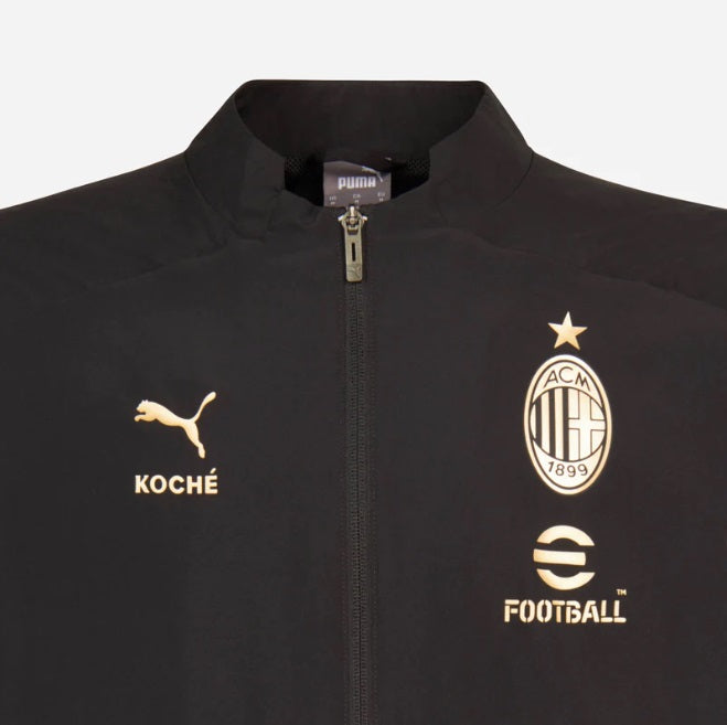 Acercamiento al escudo circular del AC Milan y logotipo de KOCHÉ aplicados en dorado metálico de alta densidad, destacando el contraste premium sobre la base negra mate de la cápsula limitada 22/23.