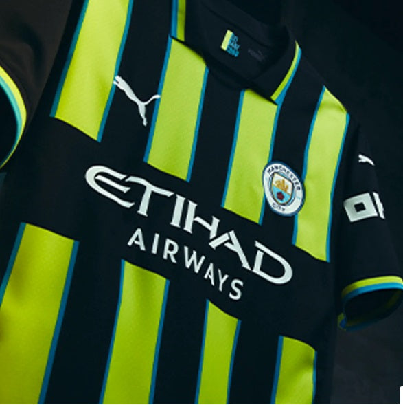 Plano detalle en ángulo del pecho con el escudo termosellado, el logotipo de PUMA y la estampa de Etihad Airways en el jersey Manchester City Authentic Match Away UEFA Champions League 2024/25 de Erling Haaland (Ref. 775085 02) en Futbol90MX.
