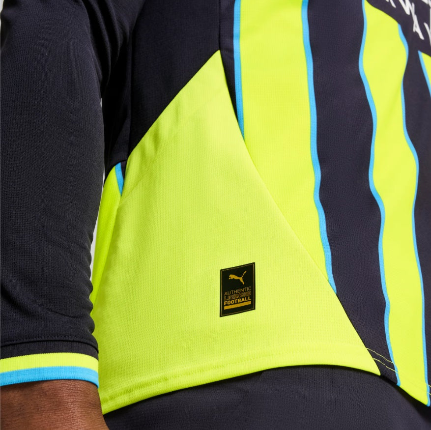 Primer plano del dobladillo inferior y la etiqueta de autenticidad Puma en el jersey de manga larga del Manchester City UCL 2024/25 de Haaland, stock Futbol90MX