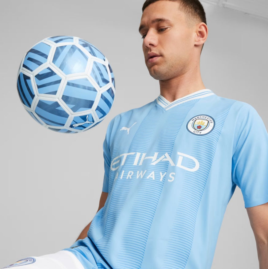 Detalle del escudo del Manchester City y logo de PUMA aplicados mediante transferencia de calor (heat-sealed) para reducir el peso.