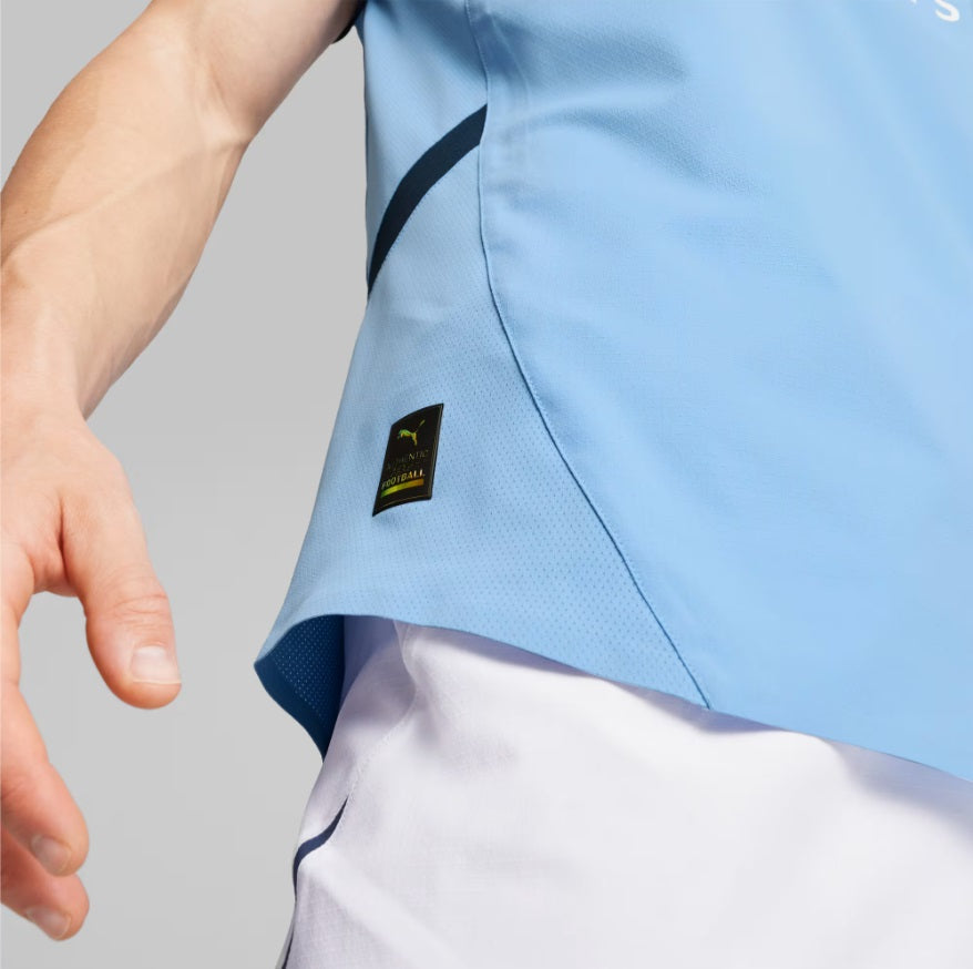 Detalle de la etiqueta de autenticidad dorada y negra en el dobladillo inferior del jersey Puma Manchester City Authentic Match Home 2024/25 (Ref. 775050 01) en la Historical Archive Boutique de Futbol90MX.