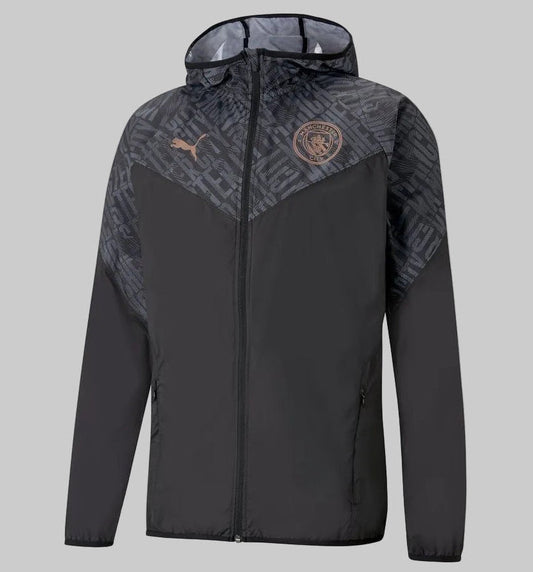Vista frontal de la chamarra de calentamiento Puma del Manchester City 2020/21 (Ref. 758699 02) en Futbol90MX, destacando su diseño en color negro, capucha integrada con patrón tonal y el escudo oficial del club.