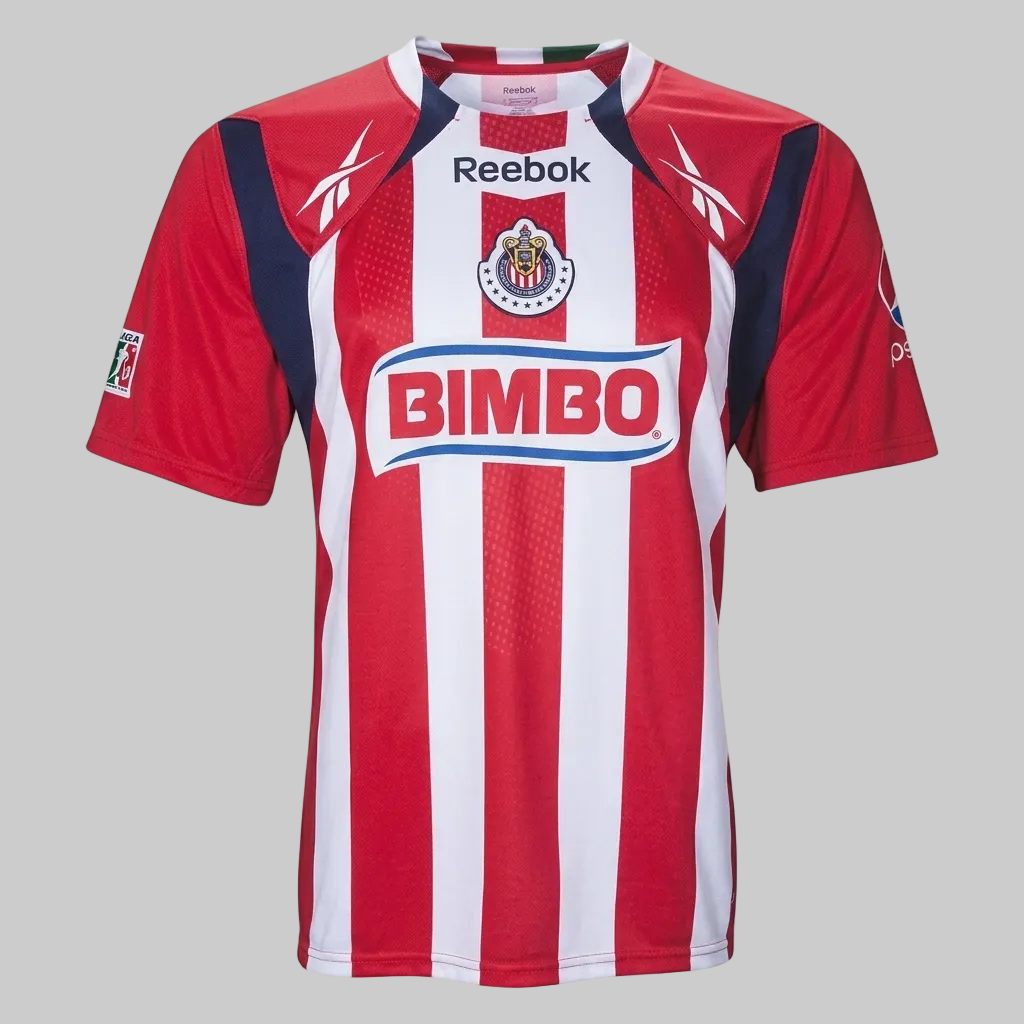 Jersey oficial de local Club Deportivo Guadalajara 2010/11 marca Reebok, vista frontal mostrando franjas rojas y blancas, patrocinador Bimbo y escudo del equipo, stock Futbol90MX