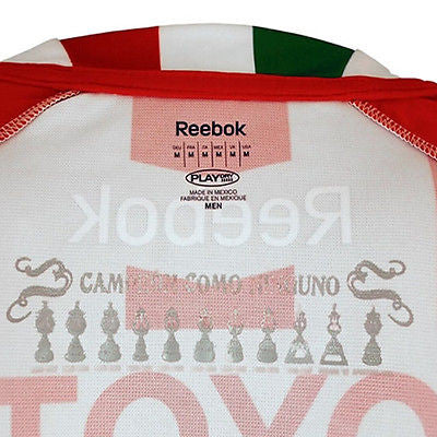 Detalle del cuello y construcción de la tela del jersey de local Chivas 2010/11, reflejando el diseño técnico distintivo de la era Reebok.