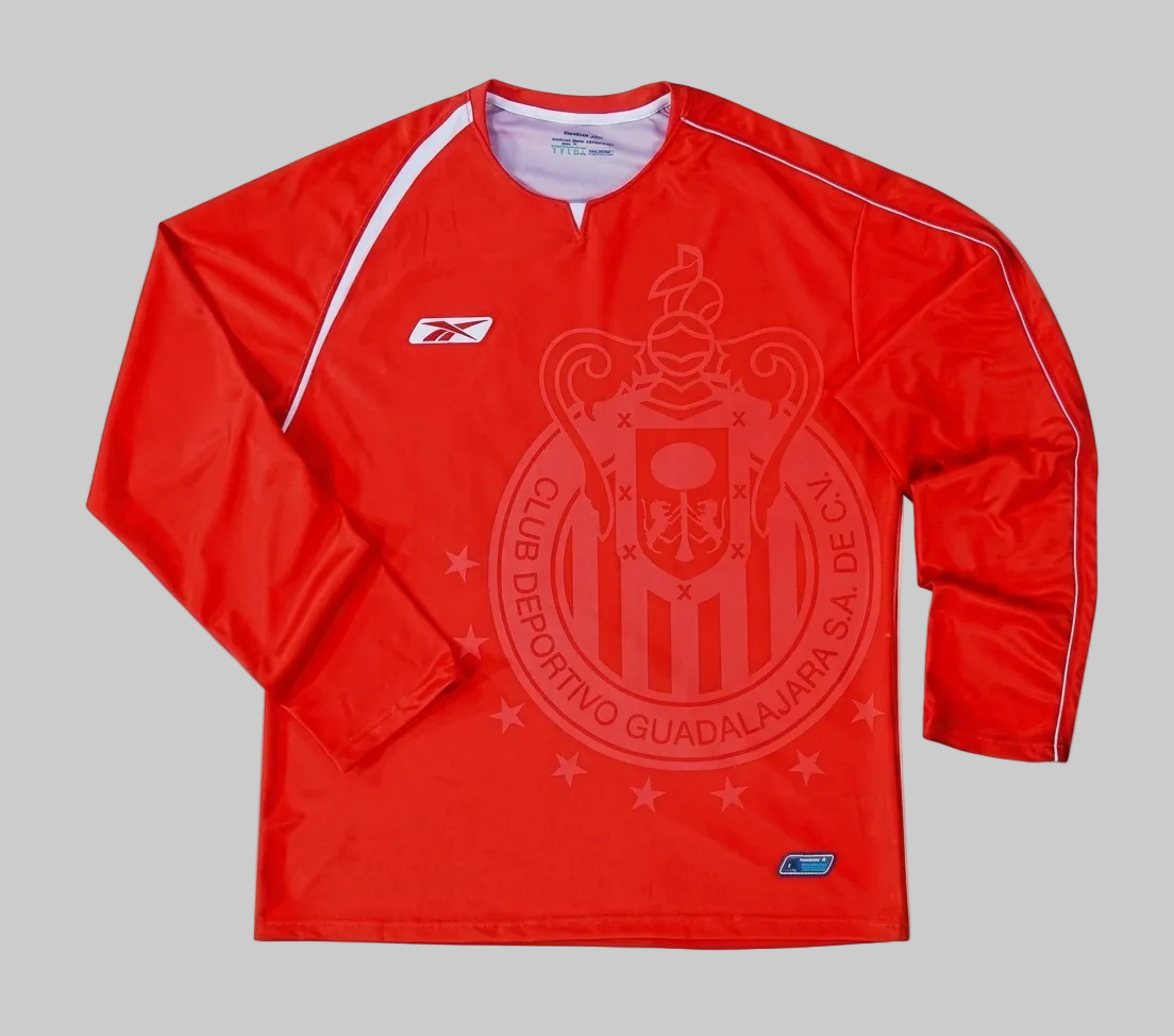 Detalle de alta resolución del tejido y escudo tonal del jersey de portero Chivas 2005-06, mostrando la integridad de la pieza de archivo.